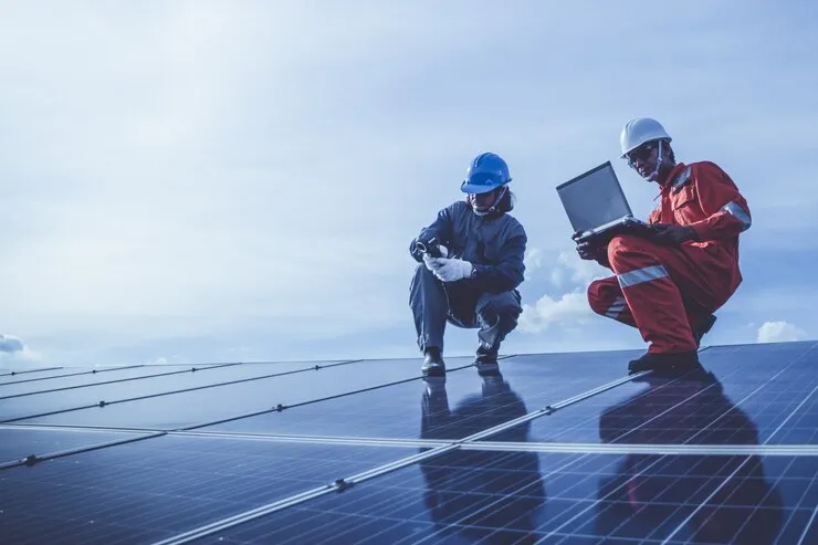 Electrical engineers reviewing a commercial solar PV installation and three-phase inverter system.